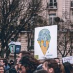 pple marching with banner of the world as a melting icecream cone