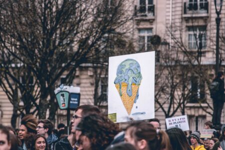 pple marching with banner of the world as a melting icecream cone