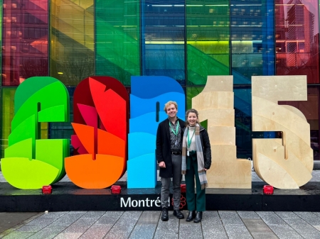 young man and woman stand in front of a colourful sut-out reading COPY15