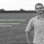 Man in a short sleeved shirt stands in a field