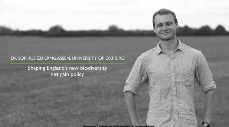 Man in a short sleeved shirt stands in a field